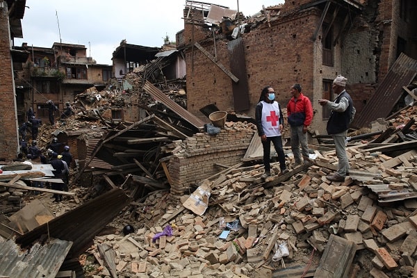 Red Cross workers standing next to damaged buildings in Nepal