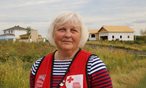 A women in a Red Cross vest standing outside in front of homes under construction