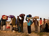 a lineup of immigrant men carrying all their belongings