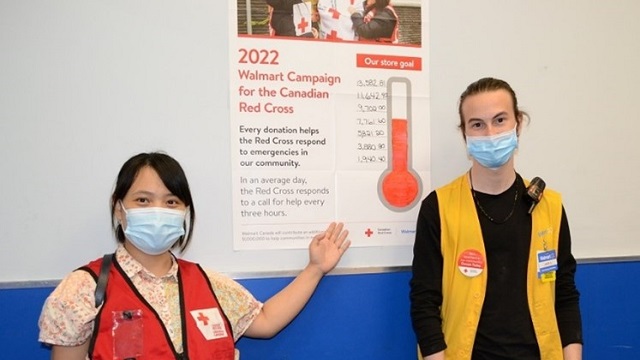 A Red Cross volunteer and a Walmart employee in front of a campaign sign