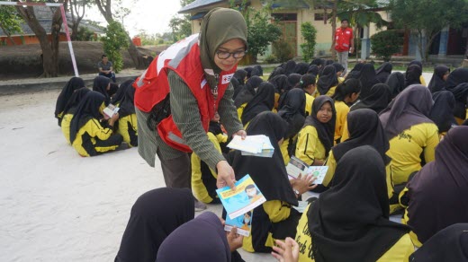 Red Cross volunteer handing out information to a group of people