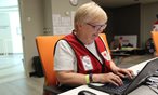woman in red vest working at a computer