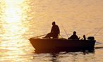 silhouette of people in a boat fishing at sunset