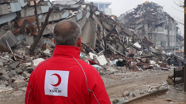 A Turkish Red Crescent worker stands in front of rubble after earthquakes in Turkey and Syria.