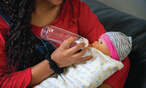 Teenage girl giving an empty bottle to a baby doll
