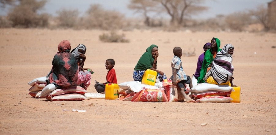 A small group of families wait for transport to take their food home.