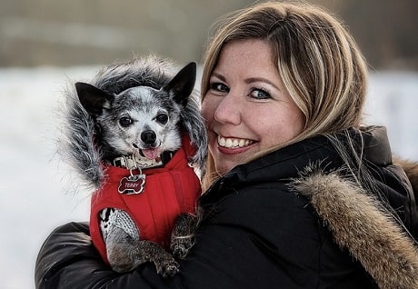 A woman smiling with a dog on her shoulder