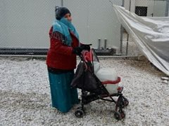 A woman with supplies in a camp hit by winter
