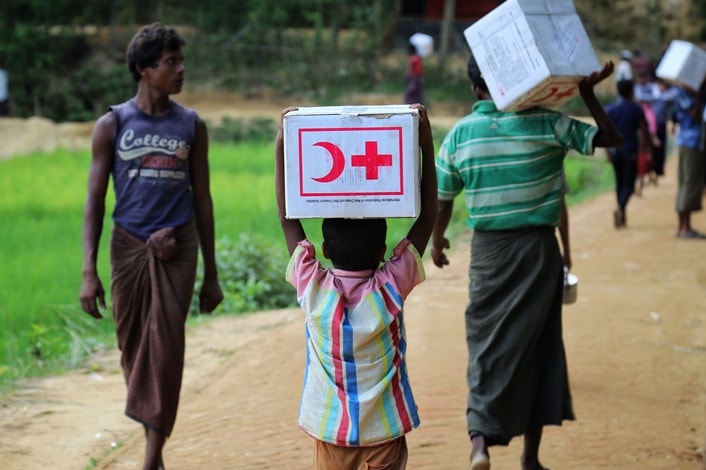People carry boxes with kits distributed by the Bangladesh Red Crescent
