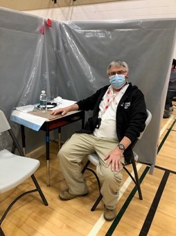 George Rudanycz siting inside vaccination centre