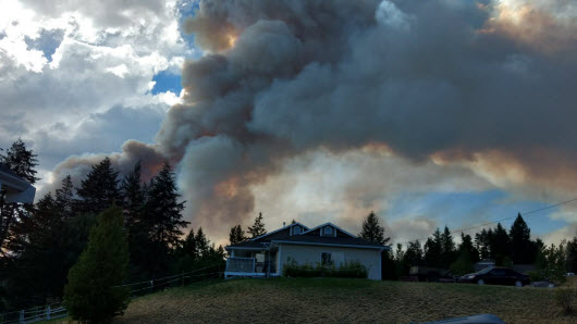 Large clouds of smoke pouring over a house.