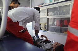 Two paramedics helping injured boy in ambulance