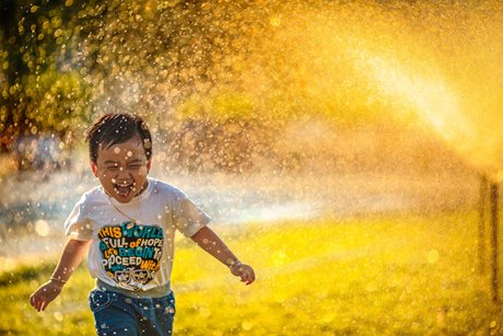 Boy playing in a sprinkler.