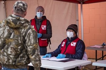 Two Red Cross team members standing in a tent talking to a resident of Fort McMurray