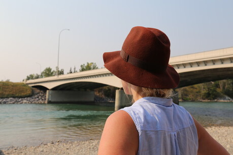 A woman in a large hat looking out at a river of water