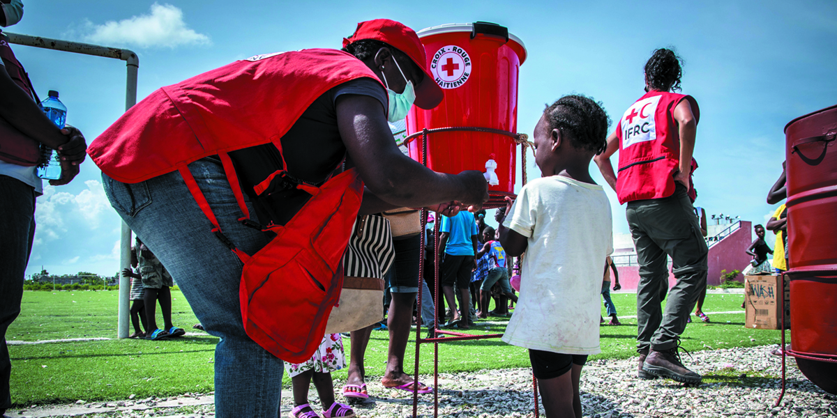 Red Cross volunteer helping little girl.