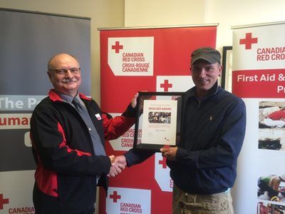 Aaron Jackson receives a certificate from Red Cross representative Barry Salmond