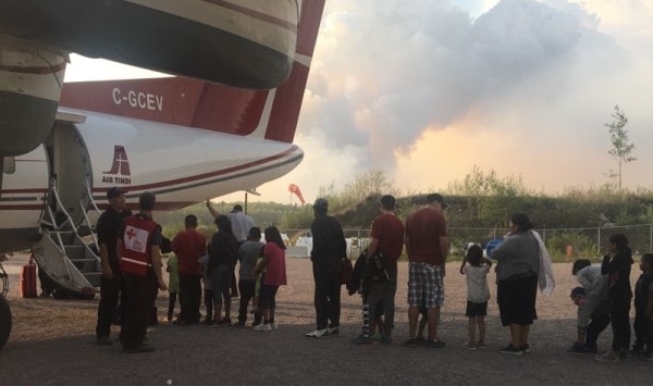 Residents of Little Grand Rapids board a plane as a wildfire is burning nearby