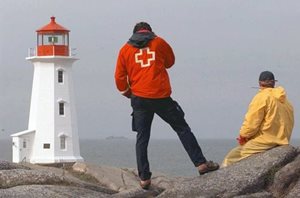 A Red Cross volunteer and a first responder standing by the lighthouse at Peggy's Cove
