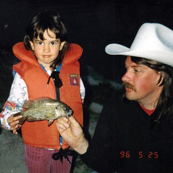 Young Sara wearing lifejacket holding a fish