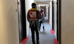 people in PPE walking in a hotel hallway