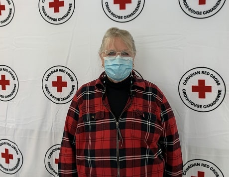 Barb standing in front of a large blanket with the Canadian Red Cross logo on it