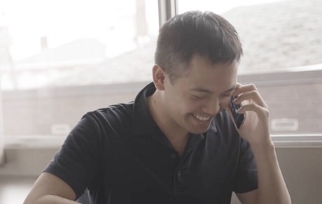 A man smiling while holding a phone to his ear