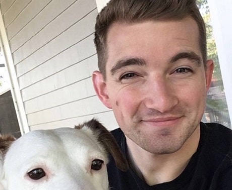 A smiling man holding a dog