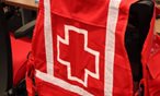 A Red Cross vest hangs on the back of a chair.