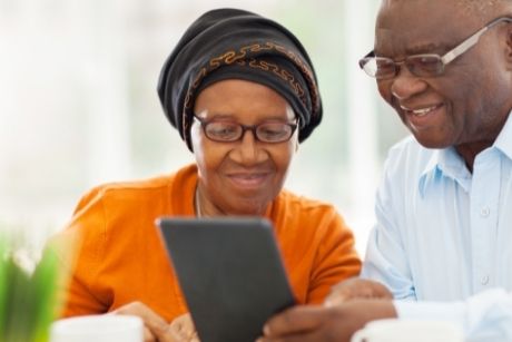 A middle aged couple look at a digital tablet, smiling