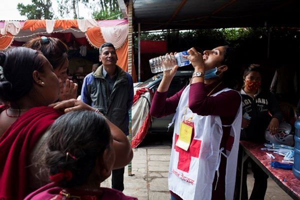 Nepal Red Cross volunteer takes a drink of purified water