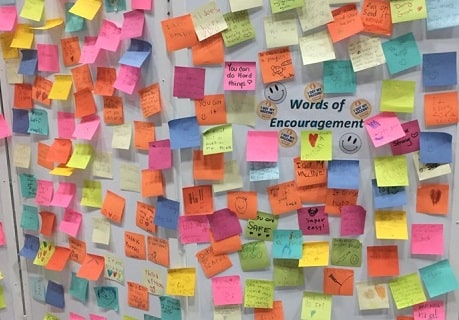 A colourful wall of post-it notes with words of encouragement written on each one