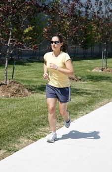 A woman in sunglasses running by blooming trees.