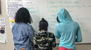 Students standing at a whiteboard.