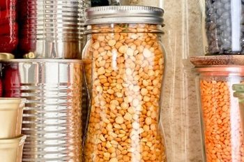 Jars and cans full of beans and legumes stocked in a pantry