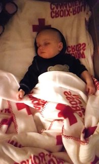 Baby Otis sleeping in a Canadian Red Cross blanket