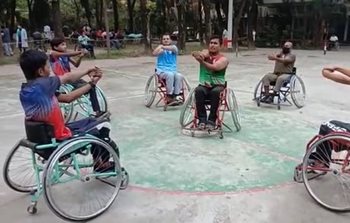 Athletes in wheelchairs in a circle stretching in a warm-up before a basketball game