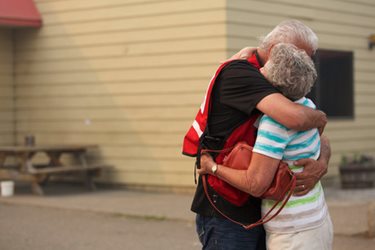Red cross volunteer hugs a wildfire evacuee