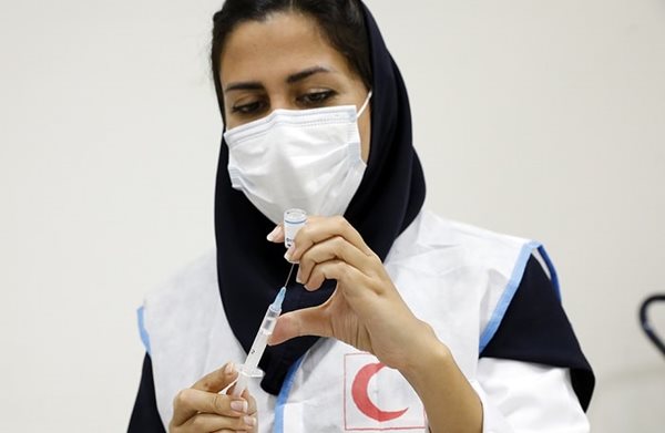 A woman in a mask filling a syringe