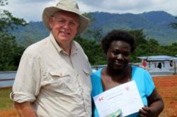 Woman poses for photograph with a Red Cross worker while she holds her certificate that shows she is Ebola-free.