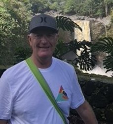 Al Stickney standing in front of a waterfall while on vacation pre-pandemic.