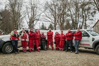 A row of Red Cross team members lined in front of two Red Cross vehicles