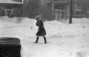 A woman covering her head during a great snow storm in Quebec in the 1970s