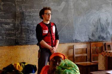 Aid worker Jean-Baptiste Lacombe stands in front of a chalkboard, wearing his Red Cross vest