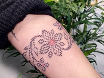A forearm with sweater rolled back to show tattoo