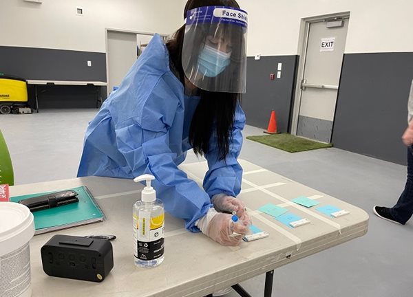 A woman in personal protective gear, such as face masks, at a table