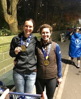 Two women smiling at the camera holding medals up