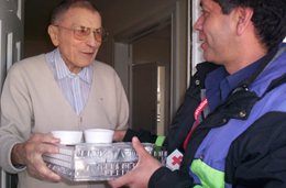 A Canadian Red Cross volunteer hand delivers packaged food to a senior citizen right at their door.