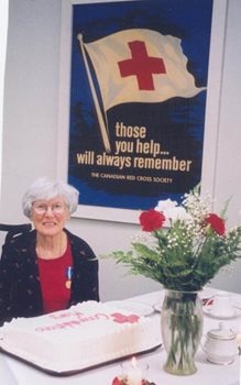 Mary Land sitting by an archived Red Cross poster and slab cake
