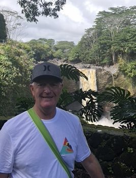 Al Stickney standing in front of a waterfall while on vacation pre-pandemic.